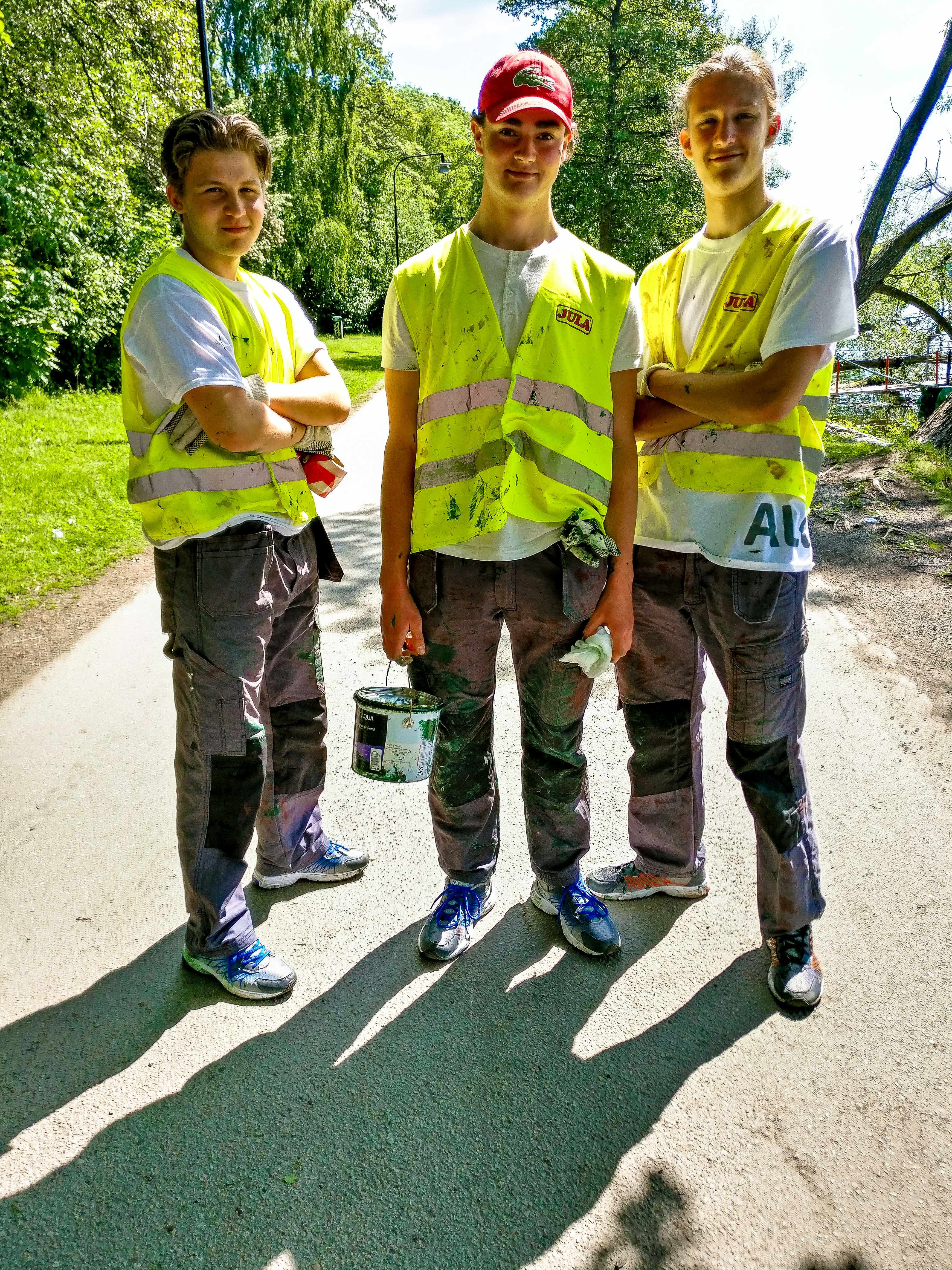 Tre unga killar med målarfärg på sommarjobb.