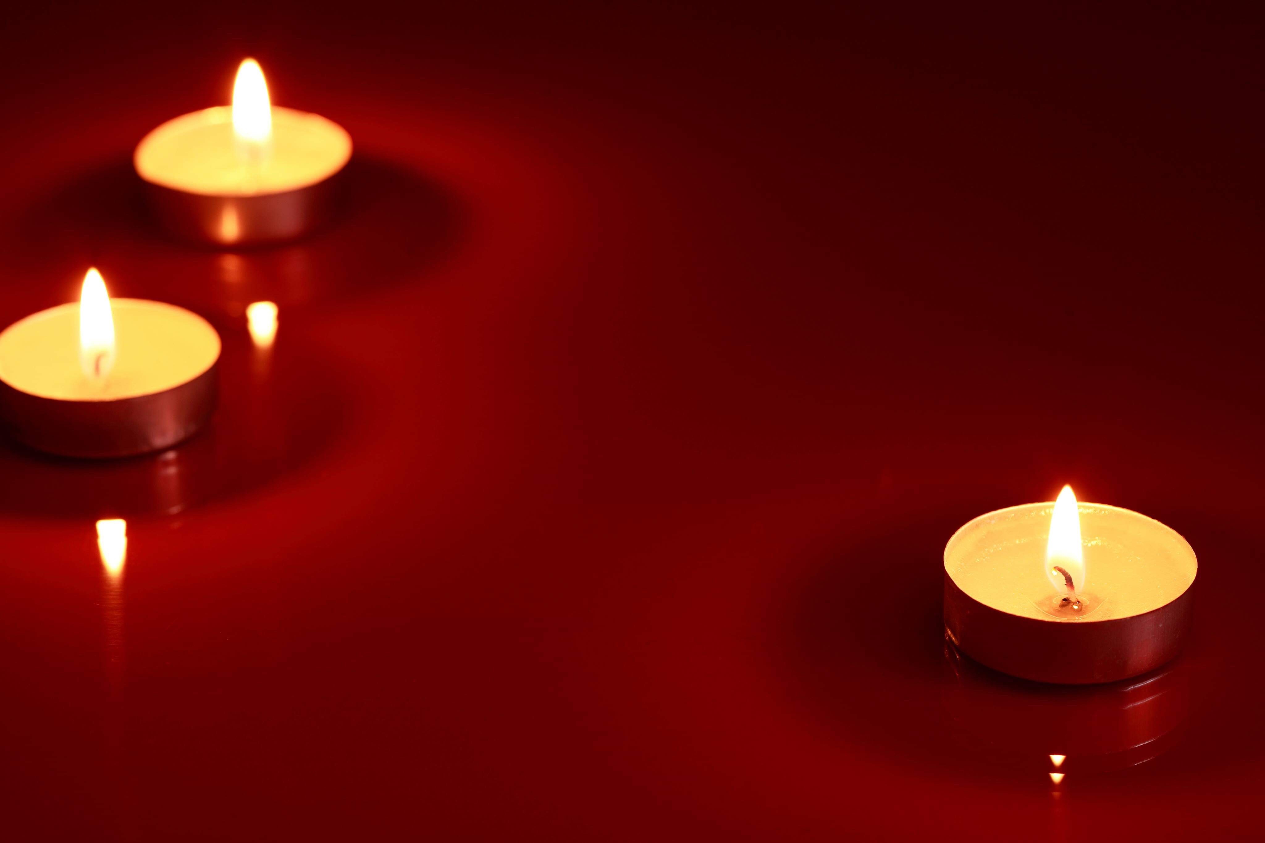 Tre ljus som brinner på ett rött bord