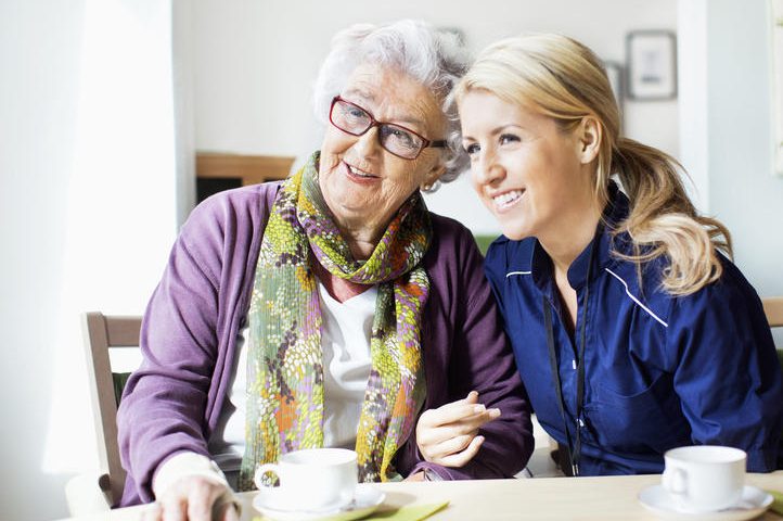 Glad pensionär på äldreboende tillsammans med personal