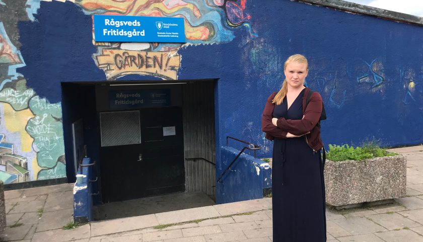 Clara Lindblom står framför den delvis övermålade graffitiväggen i Rågsveds centrum